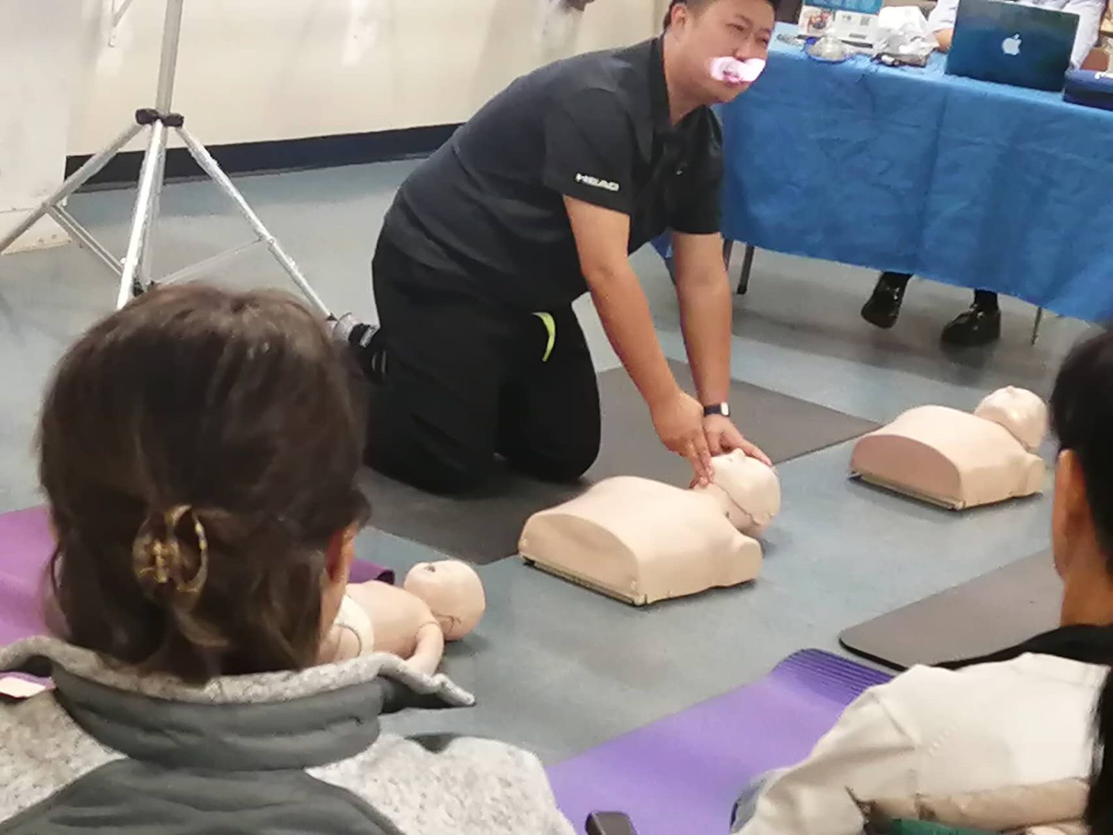 L'instructeur Shengbo Yu démontre la position de la tête sur un mannequin de RCR devant le groupe